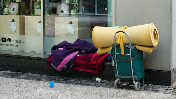 Taschen und Decken einer obdachlosen Person vor einem Schaufenster