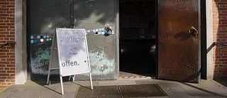 Offene Kirchentür mit einem Hinweisschild zur Öffnung