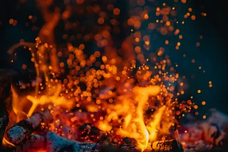 Lagerfeuer mit Funken, im Hintergrund dunkel